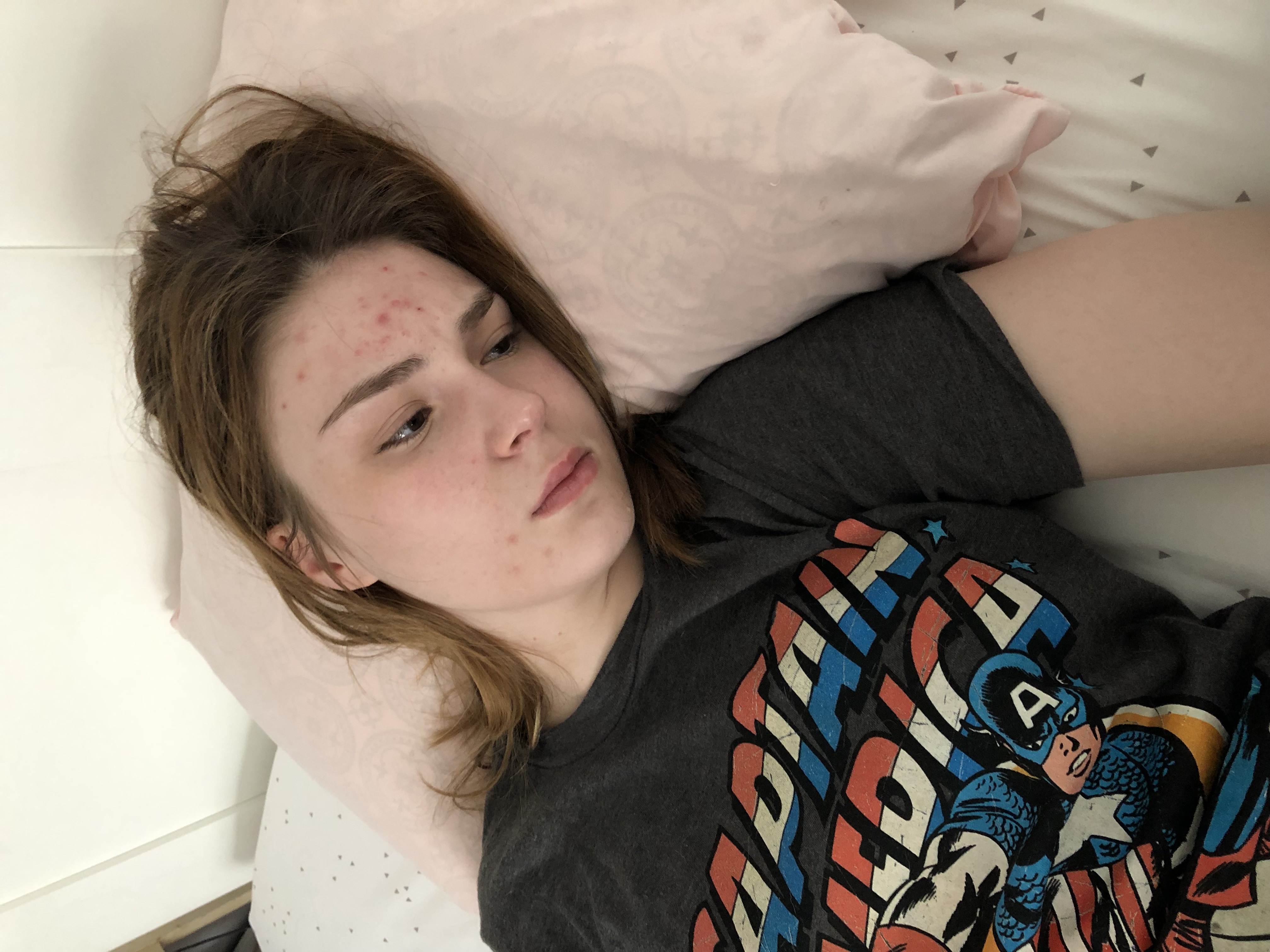 Young woman laying on bed with a Captain America T-shirt on.